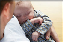 baby sleeping in a new dad's arms