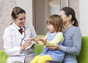 Mother with a toddler in her lap is talking to a doctor