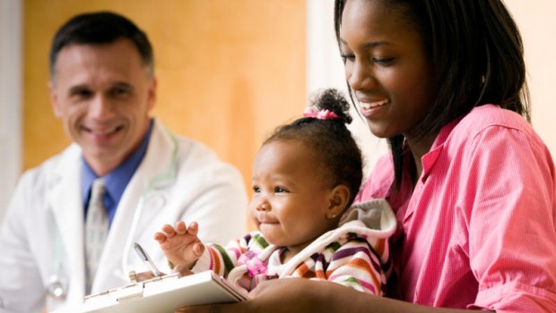 Mother with a baby in her lap is talking to a doctor