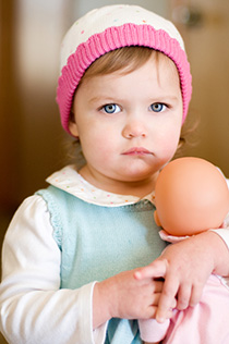 Toddler girl holding a baby doll